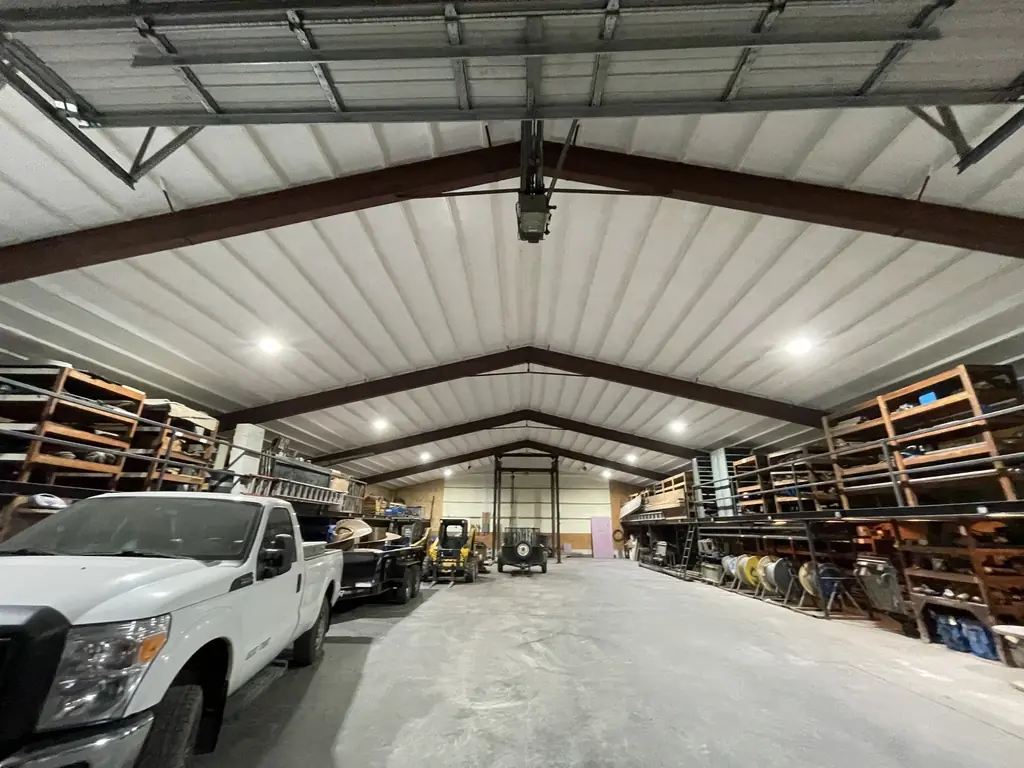 Large steel shop with closed-cell foam sprayed on the roof and walls, trucks and shelving inside